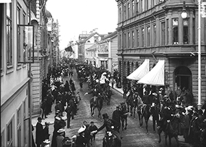 En gata med mycket folk, en parad och män i uniform