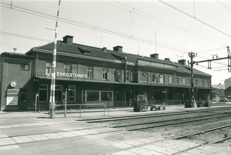 Järnvägsstationen Eskilstuna Central, en byggnad med skylt 'Eskilstuna C' och järnvägsspår i förgrunden