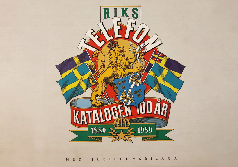 Rikstelefonkatalogen med jubileumsbilaga, visar ett illustrerat lejon, sköldar och svenska flaggor för att fira 100 år (1889–1989)