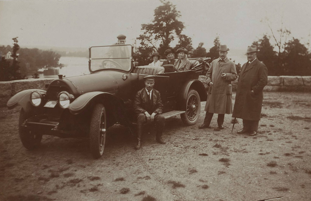 Ett fotografi från början av 1900-talet som visar en öppen bil med flera personer poserande vid fordonet