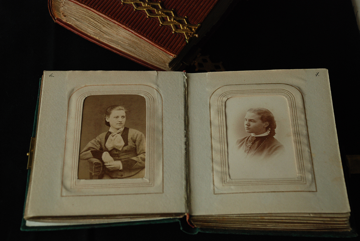 Uppslaget fotoalbum, vänstra sidan med en svartvit porträttbild av en ung kvinna. Den högra sidan med en svartvit porträttbild av en flicka.