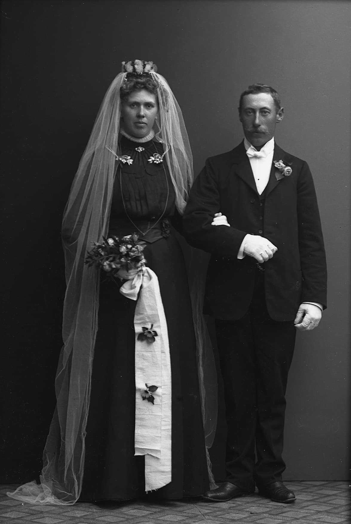 Ett äldre fotografi av ett brudpar i bröllopsklädsel.