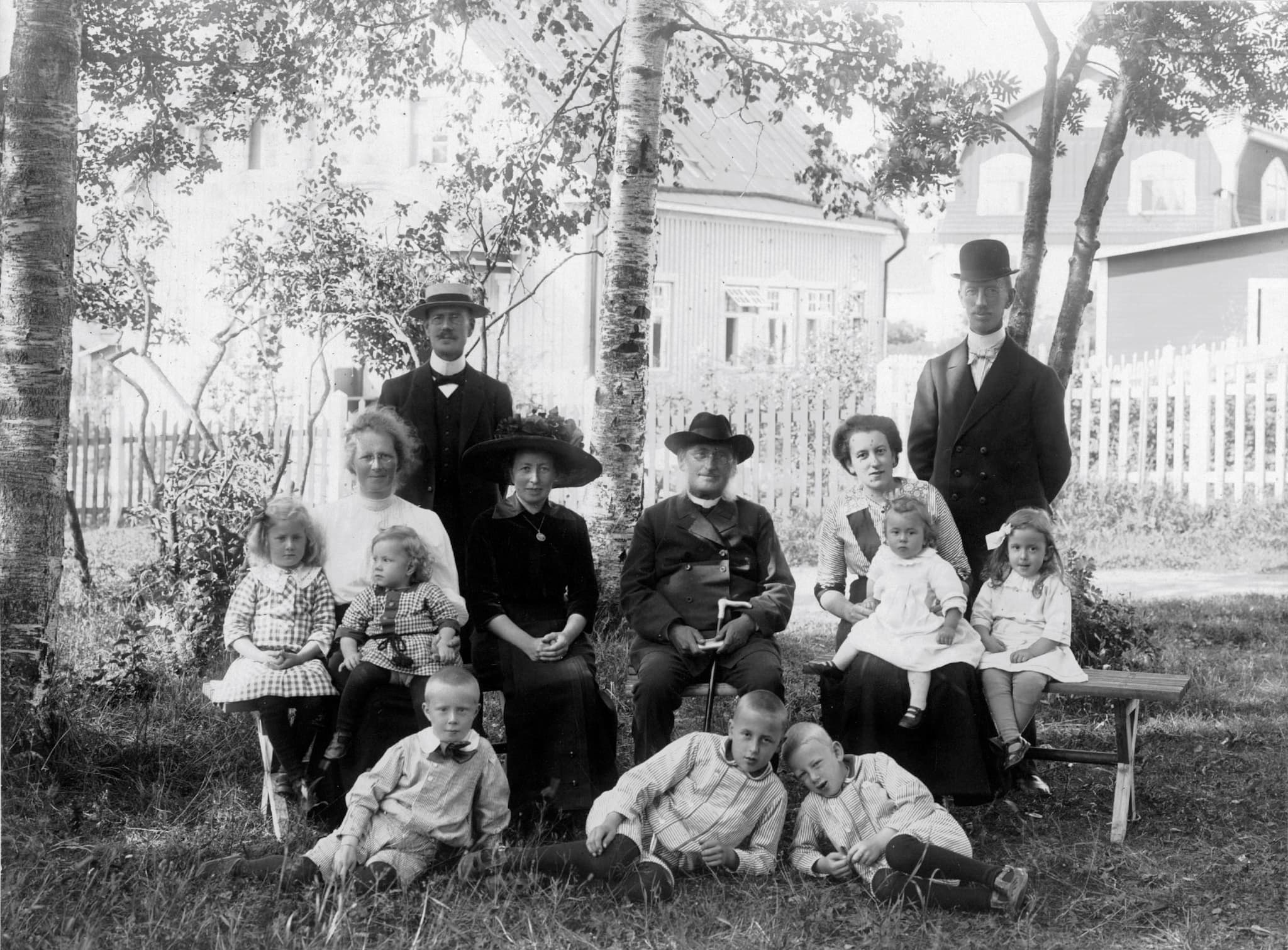 Familjebild tagen utomhus. I bilden finns sex vuxna och sju barn. Några har hattar på sig. Bilden ser ut att vara från tidigt 1900-tal.