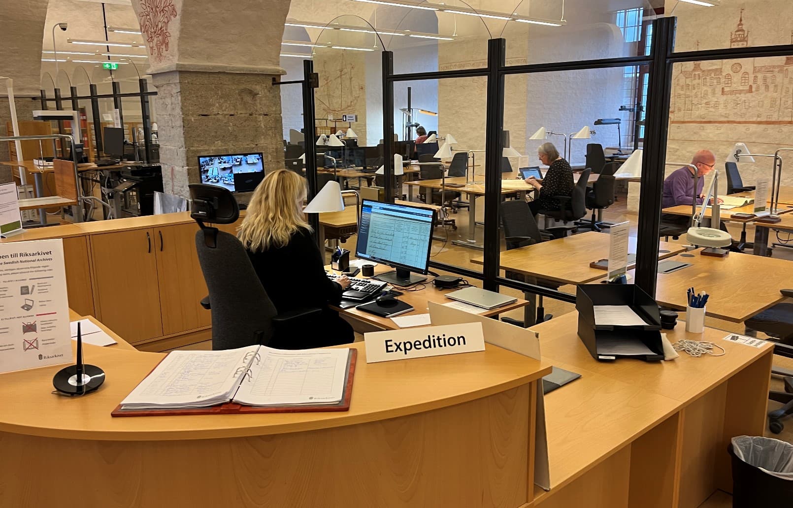 Kvinna i expedition framför läsesal.