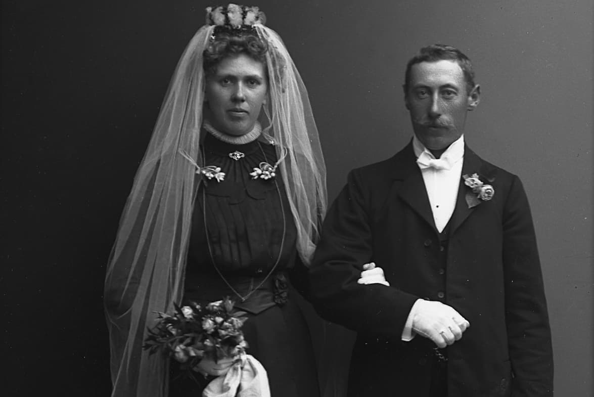 Ett äldre fotografi av ett brudpar i bröllopsklädsel.