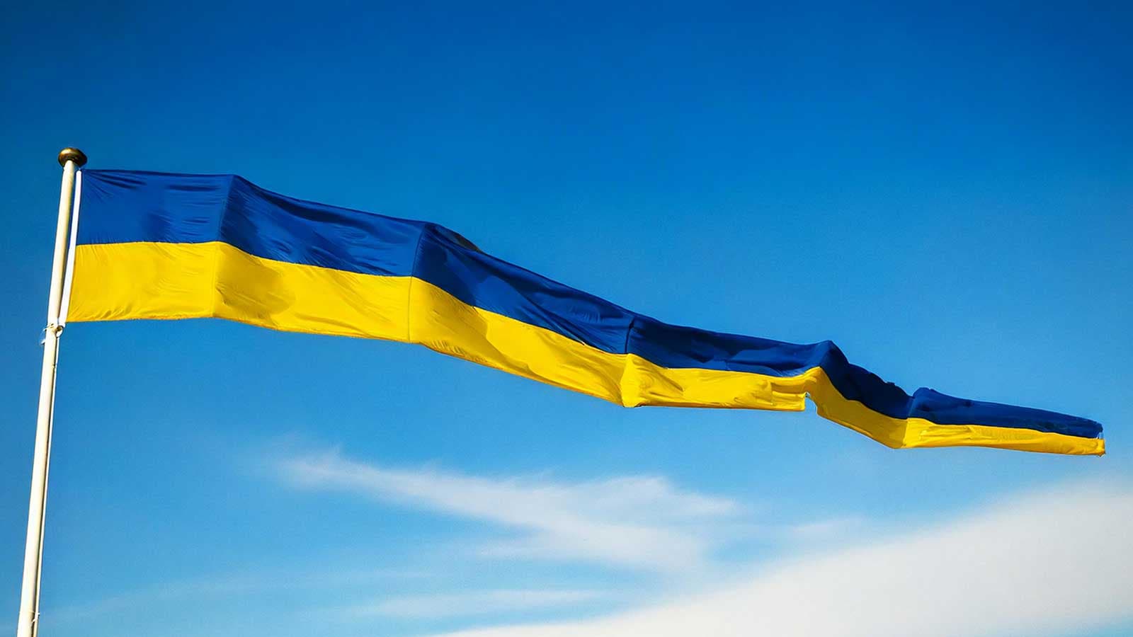 En blå och gul vimpel som vajar i vinden mot en klarblå himmel.
