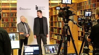 Två personer står framför kameror och skärmar