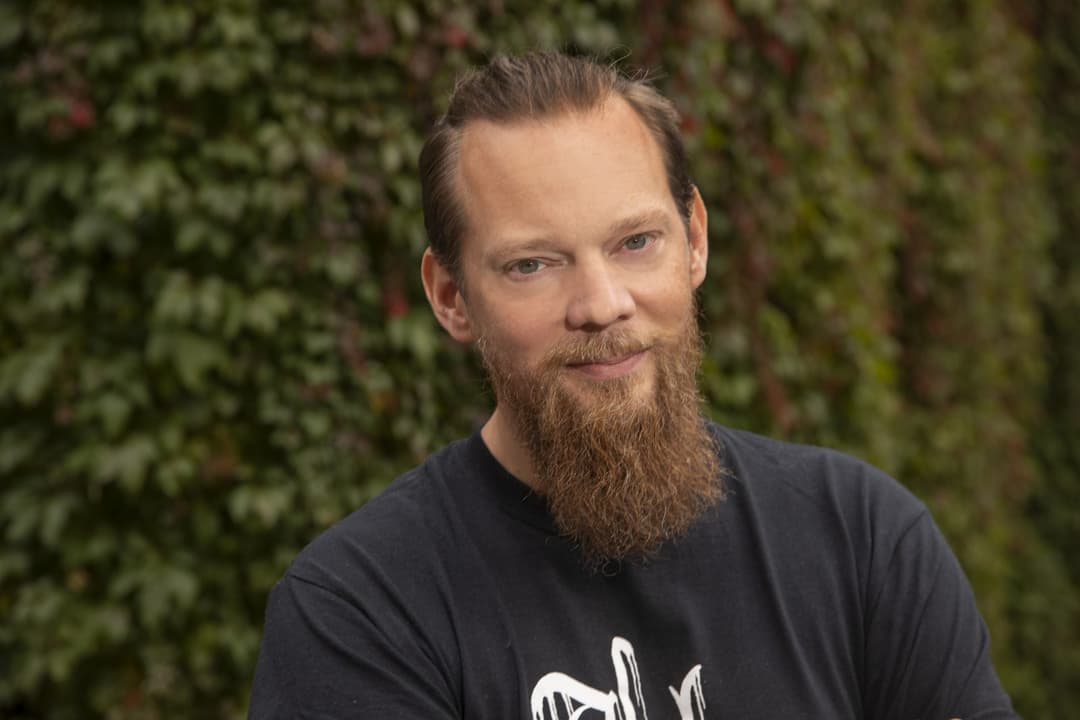 Porträtt av en man framför grönska