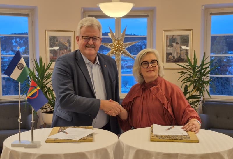 Två personer skakar hand framför dokument