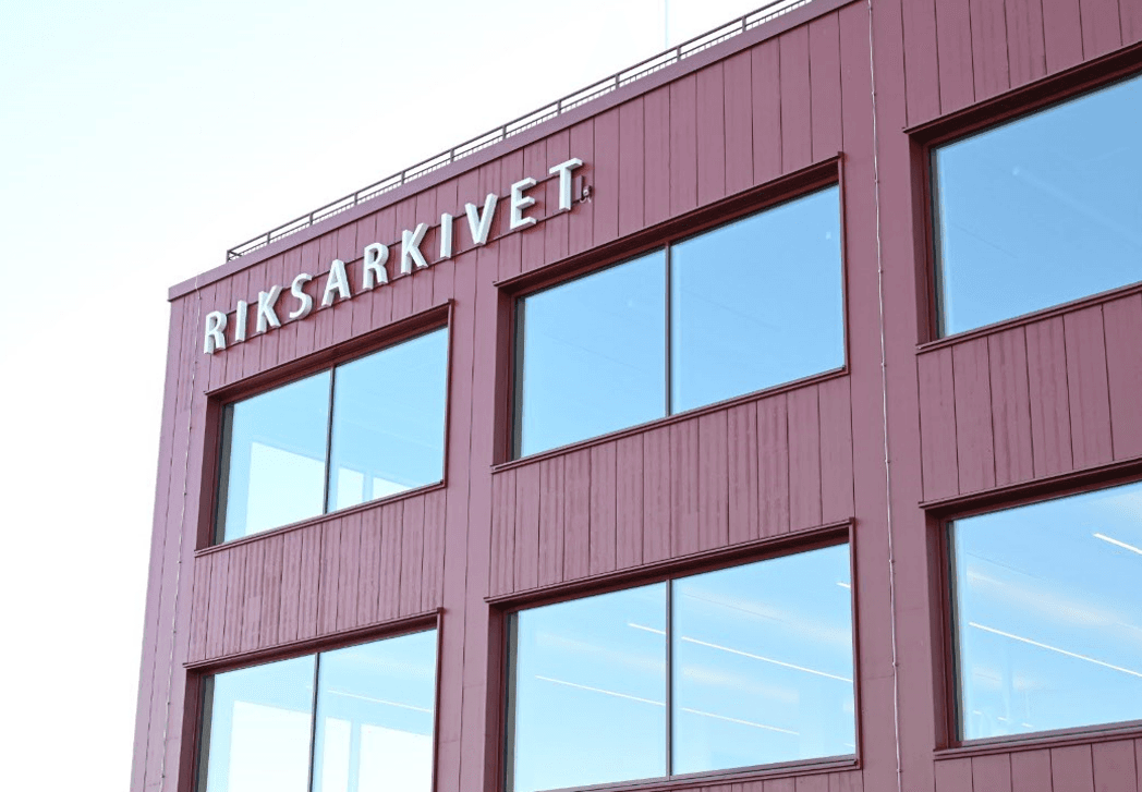 Fasad på röd byggnad och stora glasfönster.