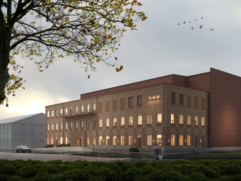 Modern tegelbyggnad med upplysta fönster i skymning.