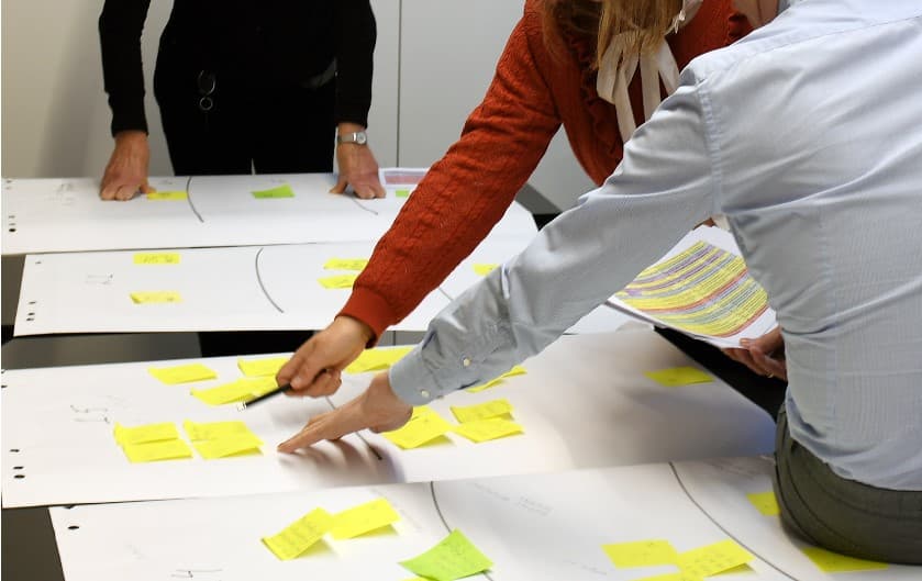 Personer vid ett bord som pekar på post it-lappar.