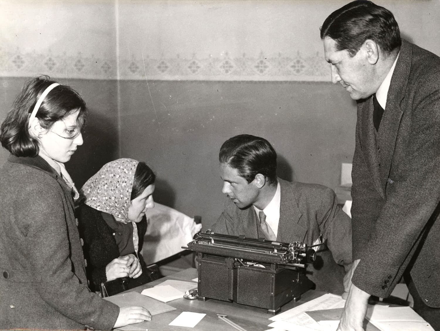 svart-vitt foto med personer runt ett skrivbord.