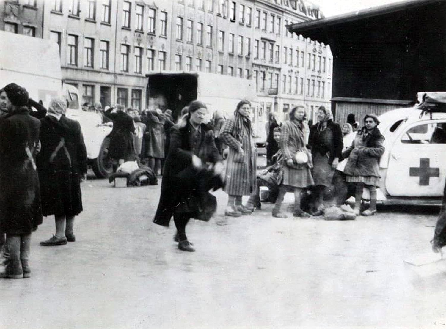 Äldre svartvitt fotografi av människor i grupper på en gata.