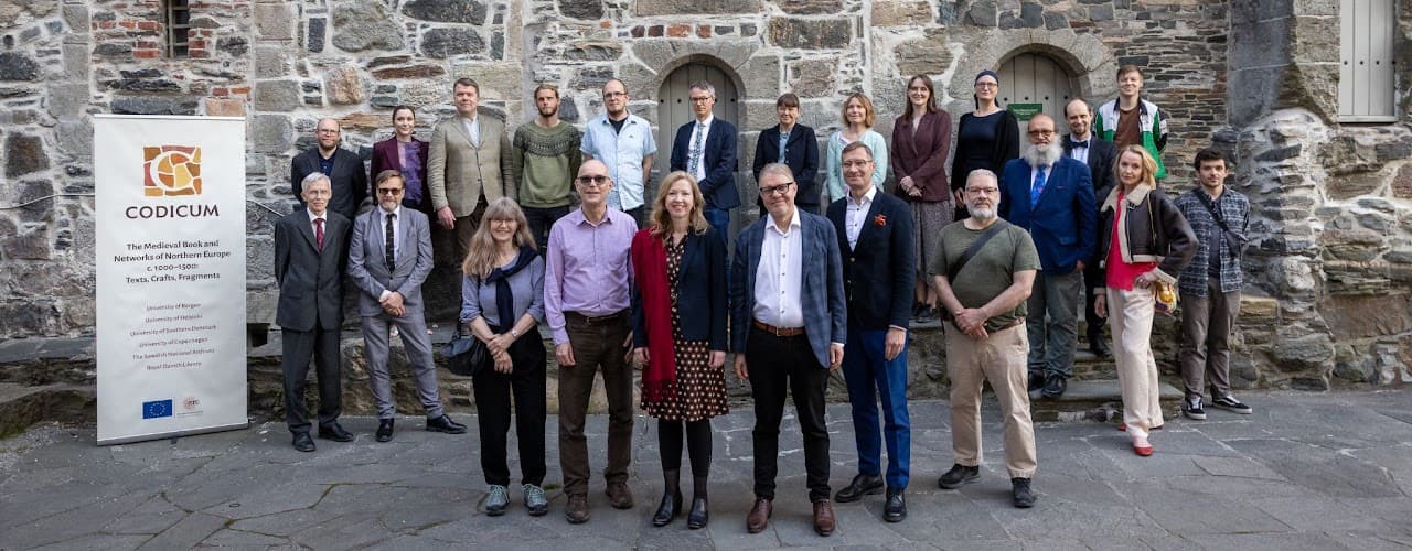 gruppbild på personer framför stenbyggnad