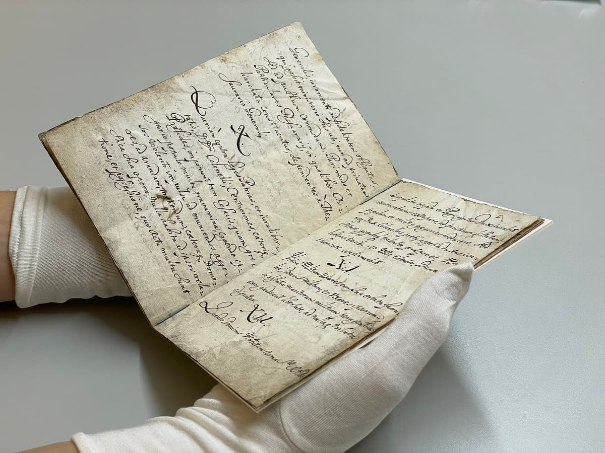 Arkivhandsksbekläda händer håller i arkivhandlingar