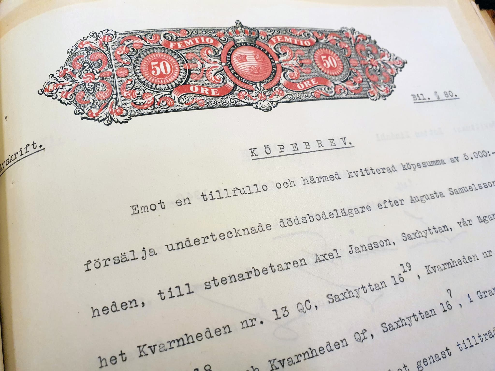 Detalj ur ett köpebrev. Ovanför texten sitter en stämpel i svart och rött med texten "femtio öre" och "beviljningsstämpel".