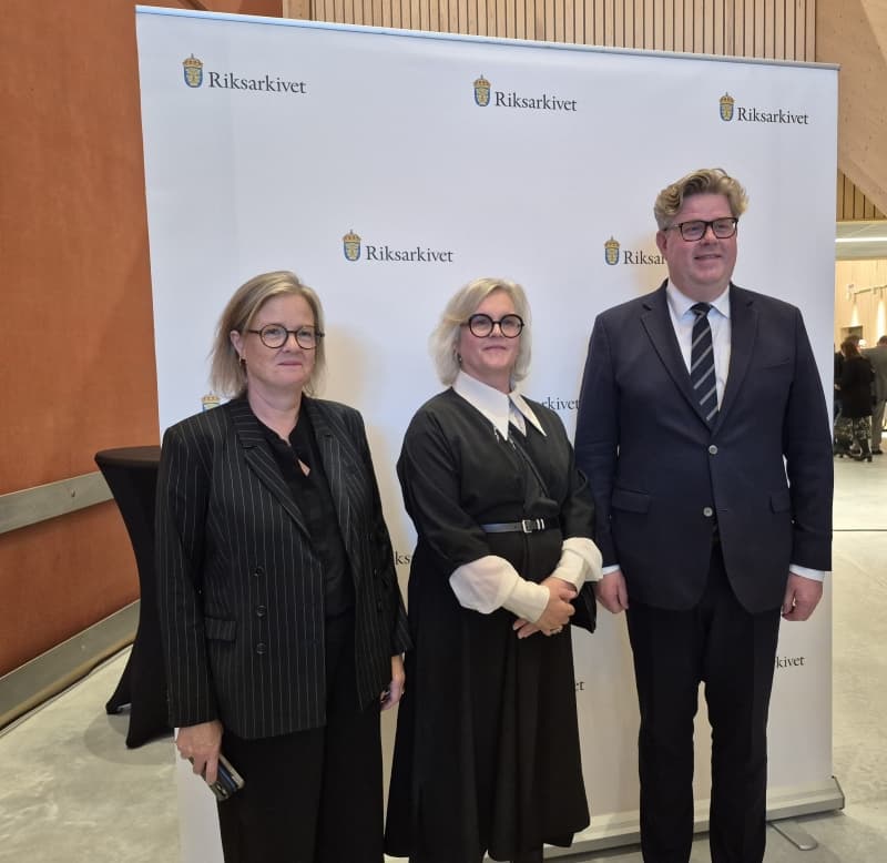 Tre personer framför en roll-up med Riksarkivets logga