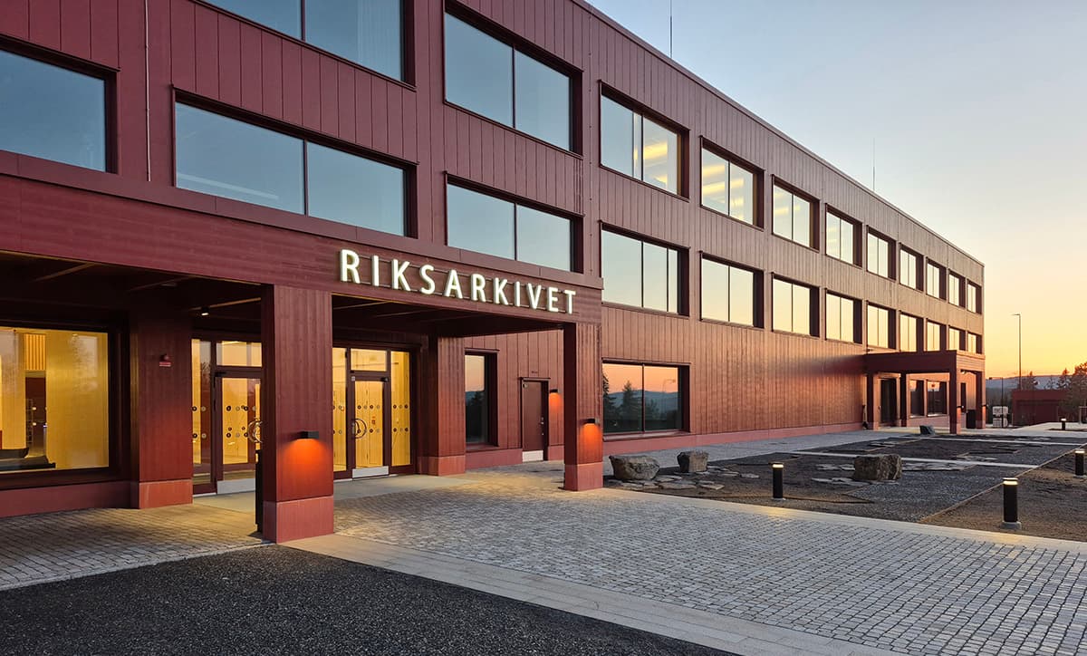 En stor byggnad med röd fasad och många fönster. Ovanför entrén står det “Riksarkivet” med stora vita bokstäver.